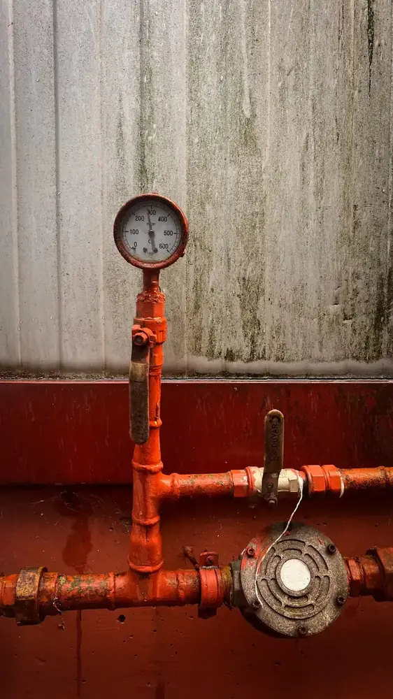 Pressure gauge attached to an outdoor hose bib showing a low reading