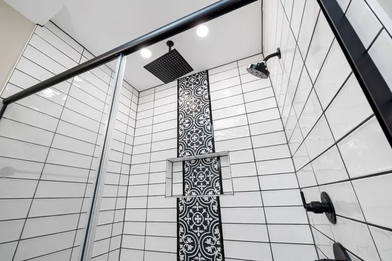 Modern shower with patterned tiled wall and black fixtures